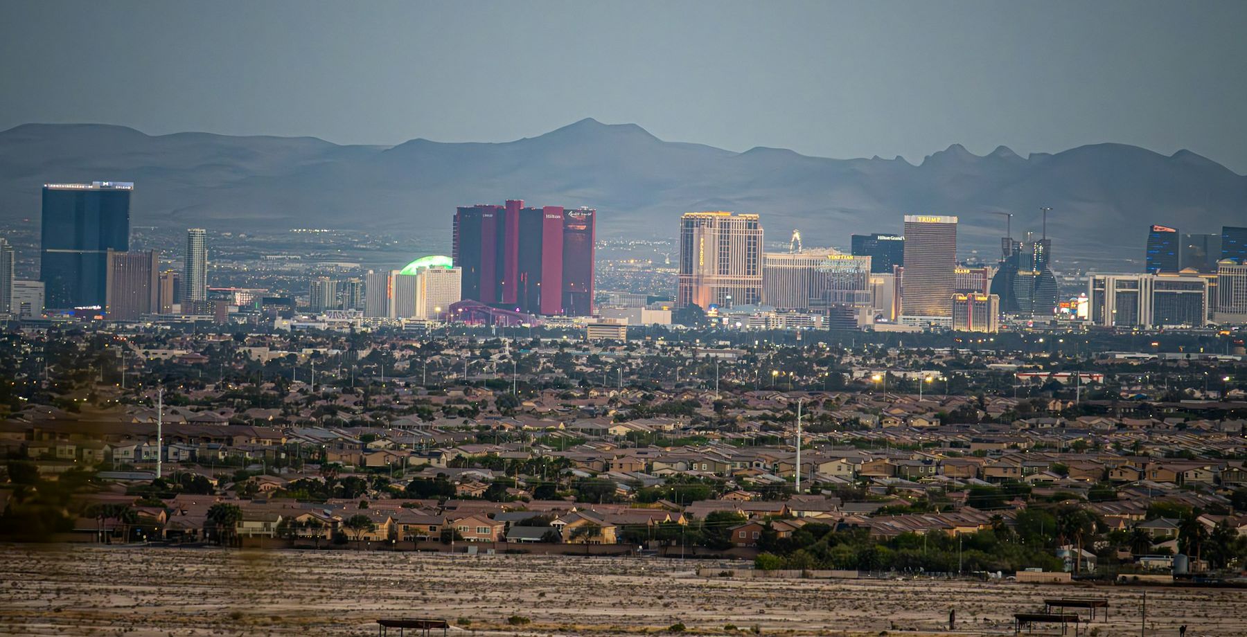 Las Vegas Valley neighborhoods with the Strip and the Spring Mountains behind them at dusk